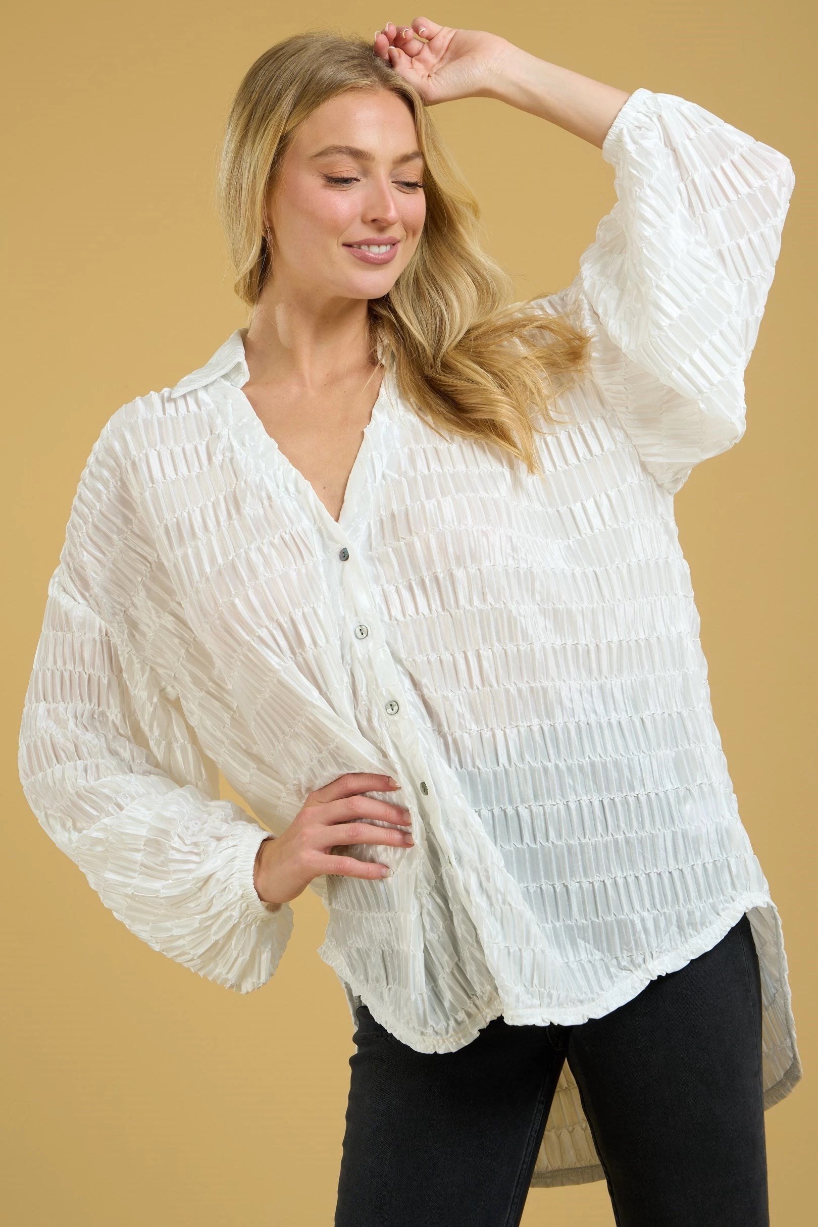 White textured oversized button down top with drop shoulder, high low hem, long sleeves, and elastic cuff.