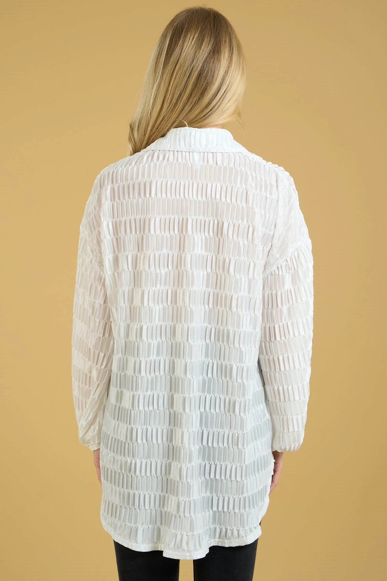 White textured oversized button down top with drop shoulder, high low hem, long sleeves, and elastic cuff.
